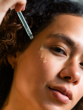 Woman Applying Skin Care Product to Her Face With Dropper