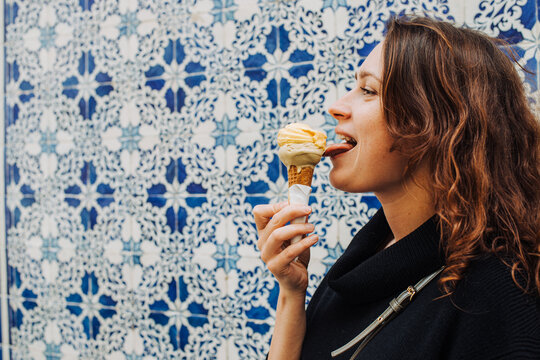Woman Licking Ice Cream Cone with Blue Tile Background