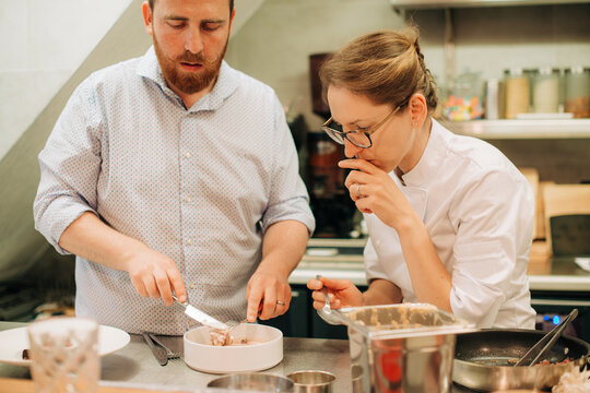 Chefs tasting gourmet dish during plating in professional kitche