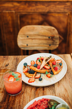 Waffles with fresh berries and chocolate on rustic cafe table