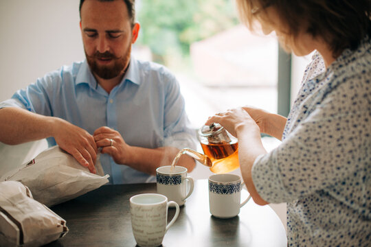 Couple preparing breakfast and pouring tea in cozy kitchen