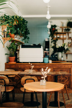 Cozy cafe interior with round wooden tables and espresso bar
