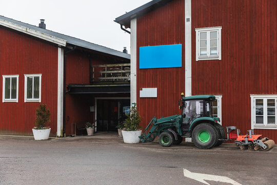 Green Agricultural Tractor Parked by Traditional Red Barn