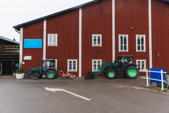 Green Agricultural Tractor Parked by Traditional Red Barn