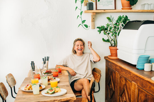 Woman relaxing at cafe brunch table with drinks and breakfast