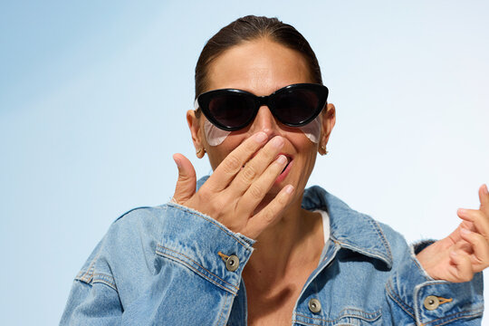 Woman Wearing Sunglasses Applies Skincare by the Beach