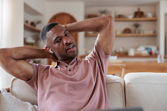Man relaxing on couch with hands behind head.