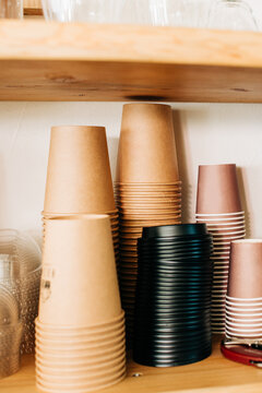Pile of disposable paper cups turned upside down on wooden shelf