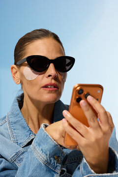 Woman Checks Smartphone While Wearing Sunglasses and Eye Patches