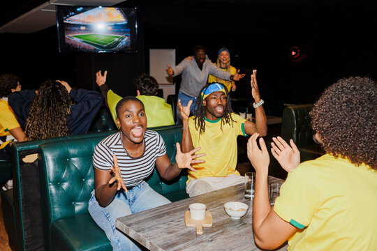 Excited soccer fans watching game in bar