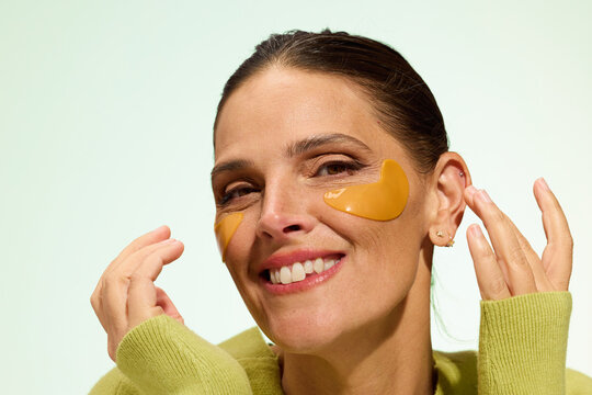 Woman Applying Skincare Patches on Her Face While Smiling