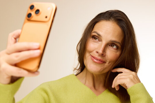 Woman Taking a Selfie With a Smartphone in a Studio Setting