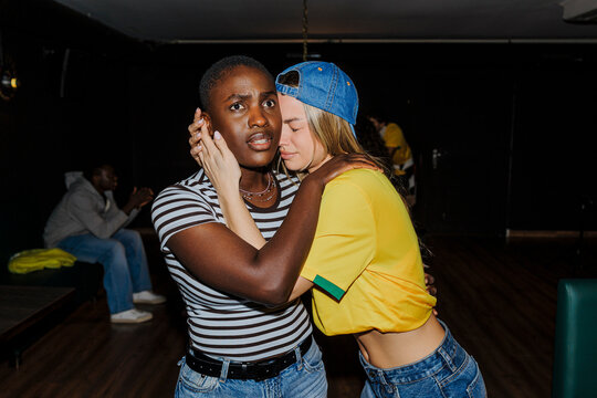 Two sad football fans hugging indoors, comforting each other.
