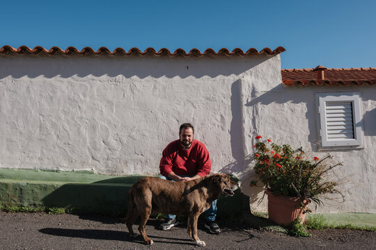 Man and dog sharing companionship outdoors near white wall