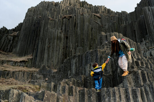 Mother and child hiking on basalt rock cliffs