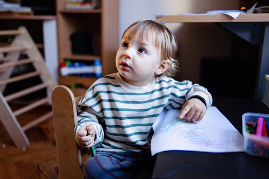 Curious Toddler Drawing With Crayons At Home Table