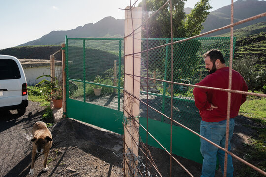 Man and dog by rural gate in mountains