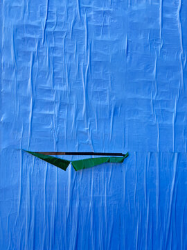 Blue Paper Wall With Wrinkled Texture and Green Tear 