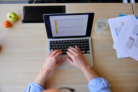 Anonymous man uses a laptop on a desk
