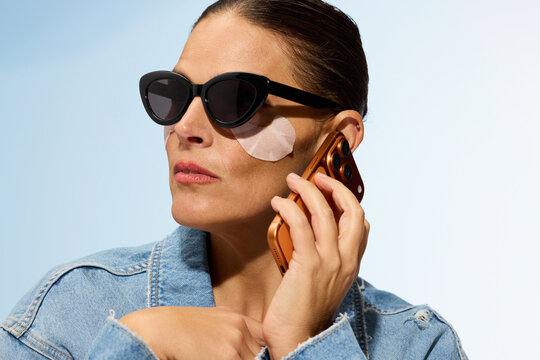 Woman Wears Sunglasses, Talks on Phone, Applies Skincare