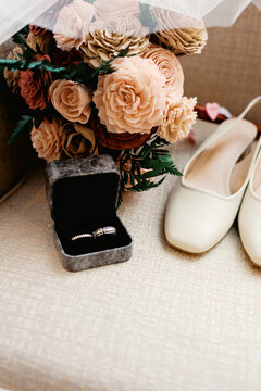 close up of ring in box and flat women's shoes and bouquet at wedding 