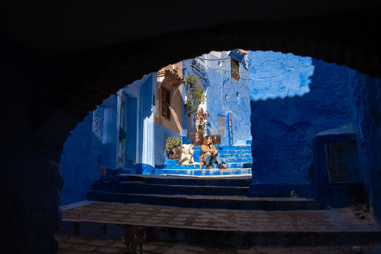 A woman sits on the stairs of the alleys of a city in Morocco