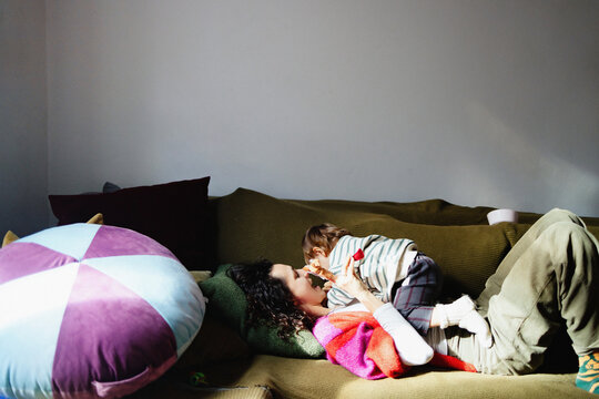 Mother and Child Cuddling Playfully on Green Sofa