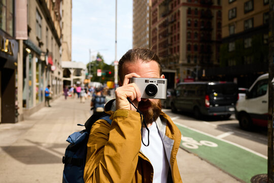 Man snaps with his digital camera on the street in Brooklyn