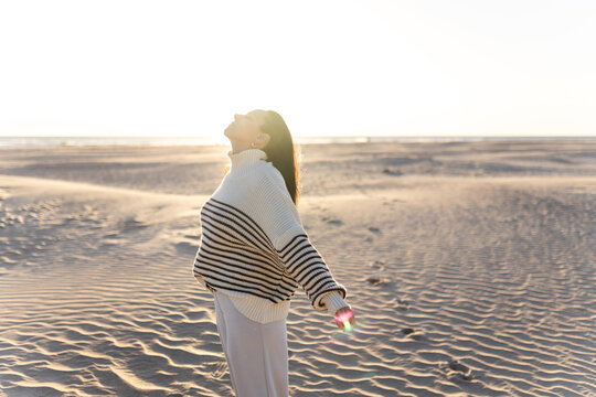 Young woman enjoying the sea breeze on a beach at sunset in winter