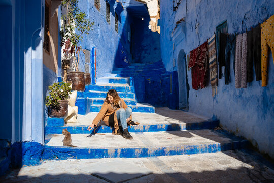 A woman sits on the stairs of the alleys of a city in Morocco
