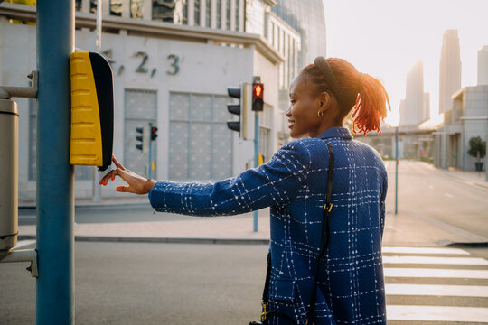 The woman presses the button to call the traffic light