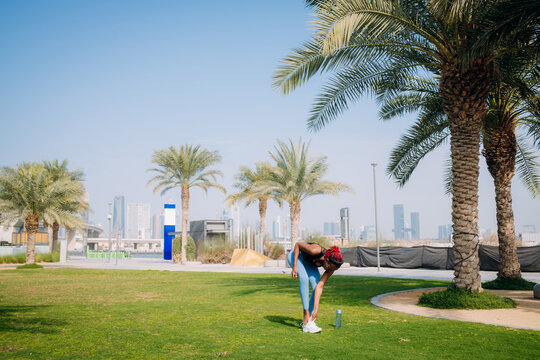 A woman ties her shoelaces on her sneakers