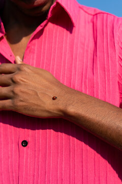 Man Wearing Pink Shirt With Ladybug on His Arm 