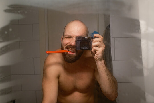 Man Brushes Teeth While Taking Selfie in Bathroom Mirror