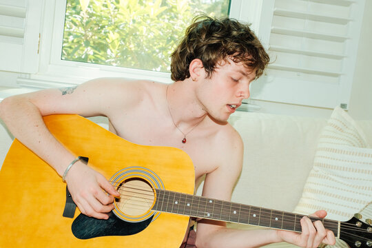 Teenager Singing and Playing Music on Guitar at Home
