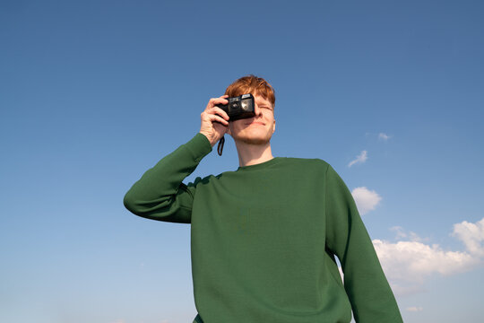 Man Takes Photo With Film Camera In Blue Sky