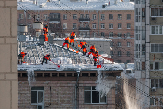Workers Clear Snow From Roofs in a City During Winter