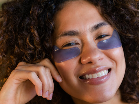 Woman Smiles While Using Under-Eye Patches at Home During the Day