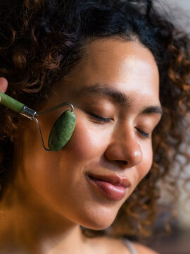 Woman massaging face using green jade roller 