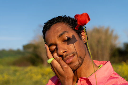 Man in Field Holding FLOWER With Eyes Closed 