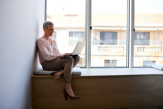 Beautiful woman works on a laptop by the window
