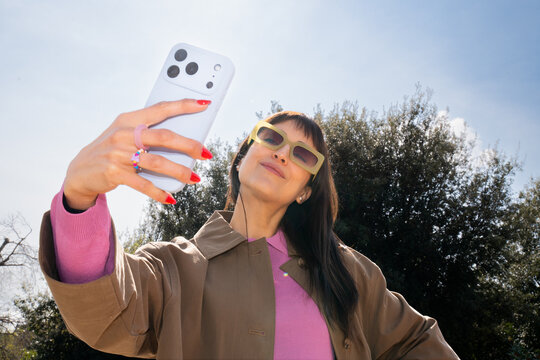 Bright spring day with young woman taking a selfie outdoors
