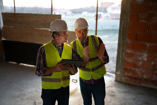Workers discuss plans at a construction site