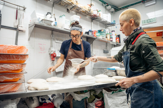 Bakers sifting flour onto fresh dough for bread