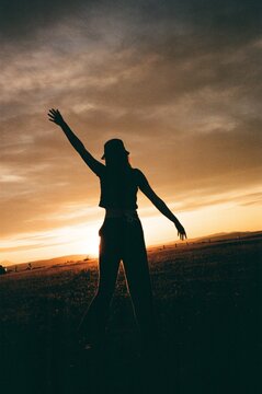 joyous silhouette of woman standing in front of sunset in field film
