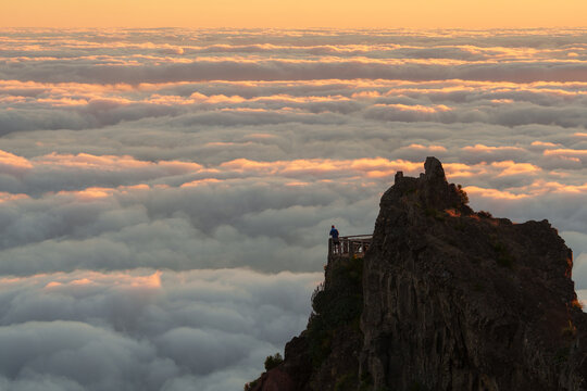 Man standing on a viewpoint above the sea of clouds 