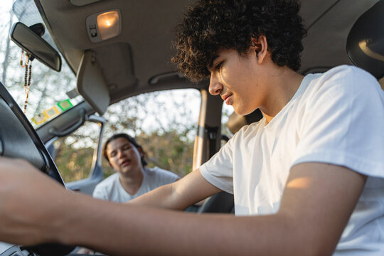 Young man learning driving from female instructor