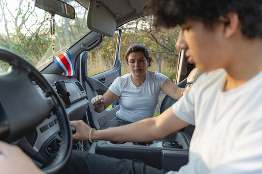 Instructor teaching young man during driving lesson in costa rica