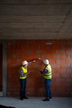 Workers talk on wall construction site