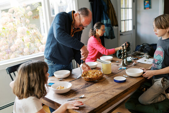 grandparents serving apple pie at table with grandchildren waiting 